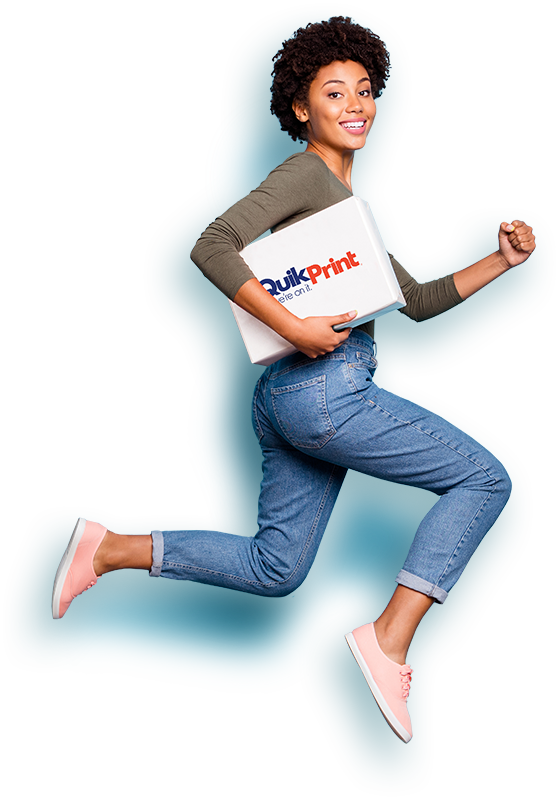 Woman jumping with a Quik Print package tucked under her arm.
