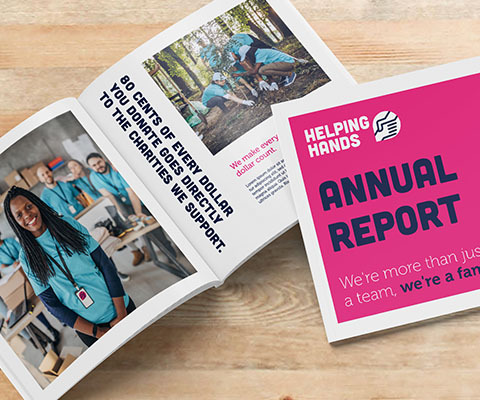 An annual report book with a pink cover sits in front of an open version of the book. The open book has images of volunteers in action.