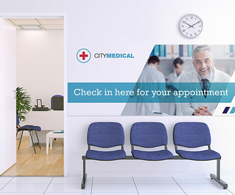 A large wall sign for City Medical with a smiling doctor. The text reads "Check in here for your appointment."