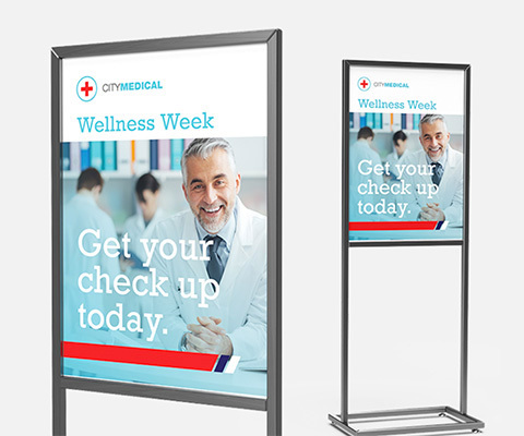 Two metal display stands with a poster that reads "City Medical Wellness Week. Get your check up today."