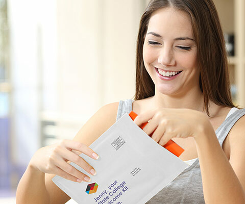 A smiling white female holds a white envelope. She is pulling out a document.