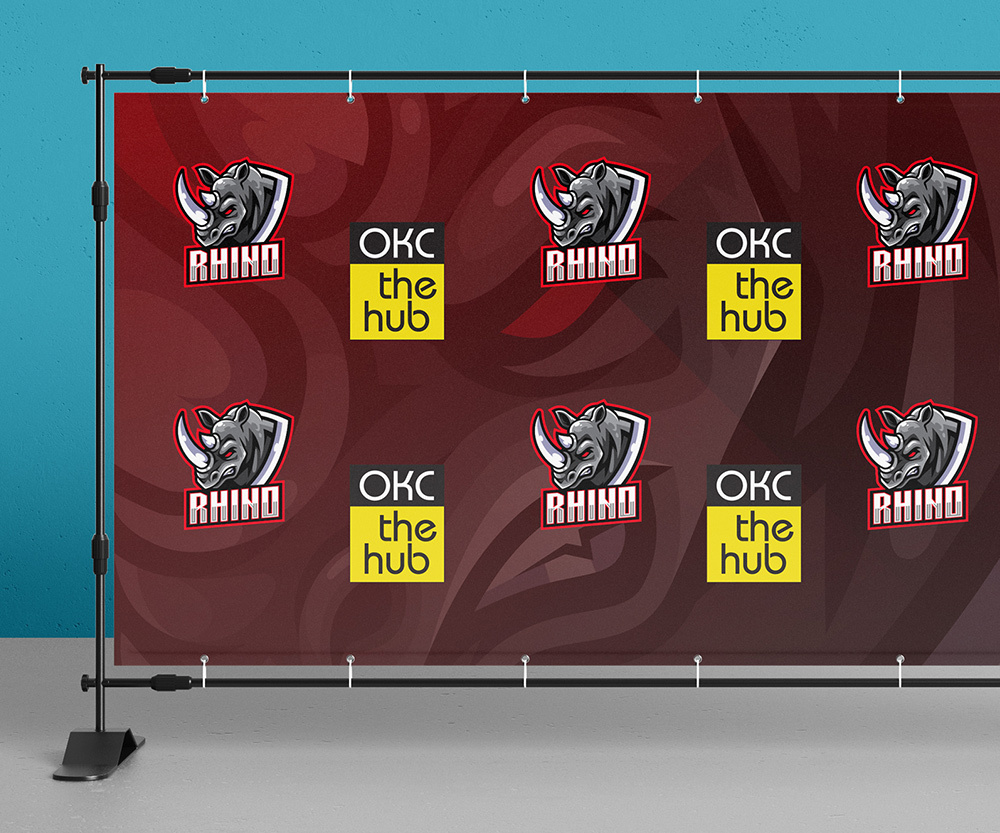 A OKC The Hub Rhino sports team step and repeat. The Rhino logo and The Hub logo repeat on a red/black background.