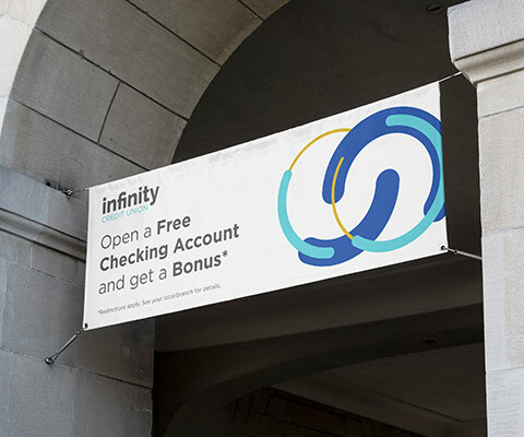 large banner hanging from a building archway. The banner is white with the infinity credit union logo and says "open a free checking account and get a bonus."